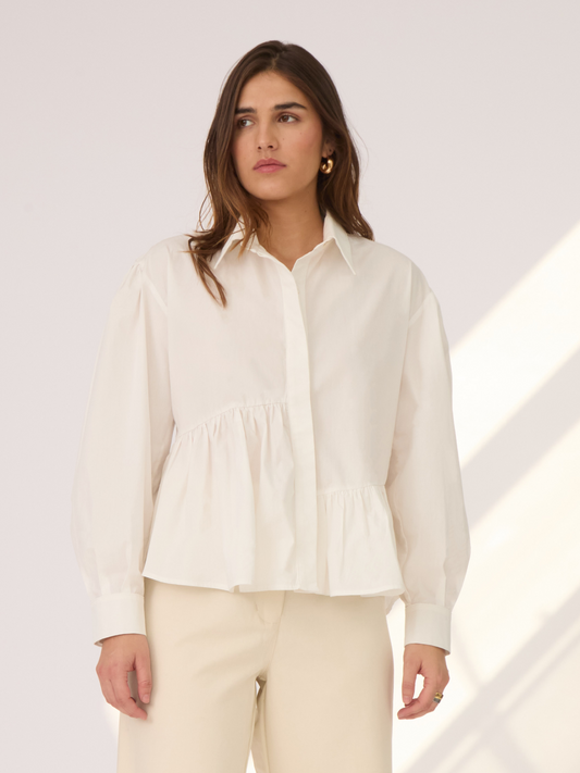La Camisa Olivia tiene un corte asimétrico, mangas globo y un largo ideal para combinar con diferentes estilos de pantalones y faldas. Esta camisa es la definición de versátil.
