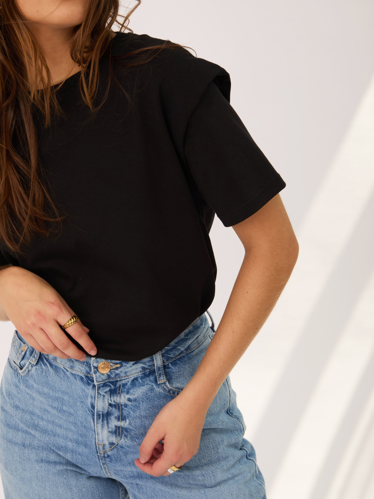 Camiseta negra con hombreras, ancha y versátil para usar por dentro o por fuera de la parte de abajo.