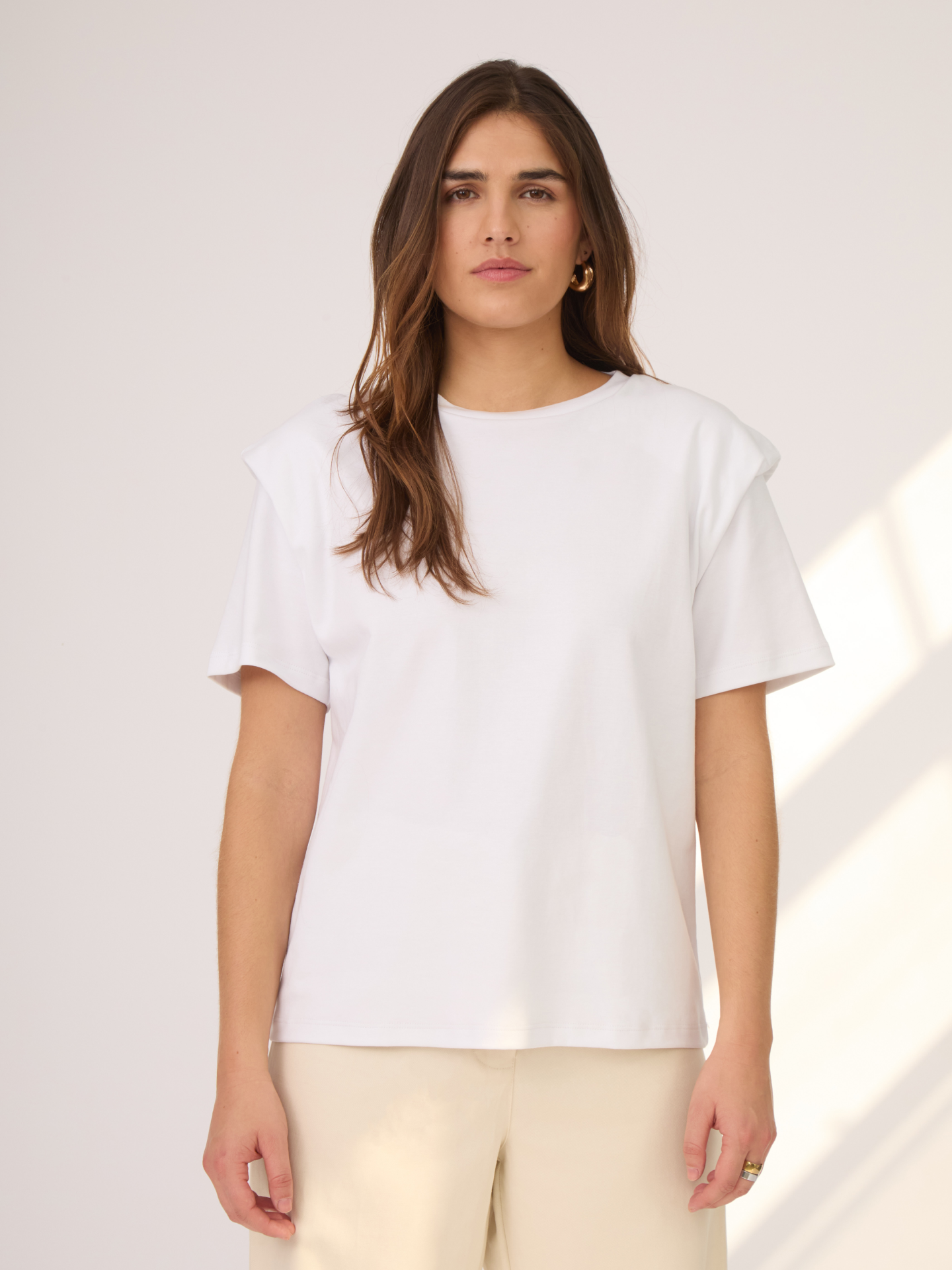 Camiseta blanca con hombreras. Un básico del closet ya que juega con cualquier look dandole un toque único y moderno.