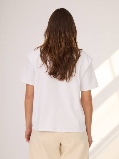 Camiseta blanca con hombreras. Ideal para tener en el closet y usar en diferentes ocasiones. Versátil para diferentes tipos de looks.