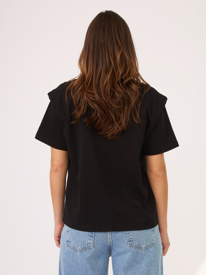 Camiseta negra con hombreras. Ideal para tener en el closet y usar en diferentes ocasiones. Versátil para diferentes tipos de looks.