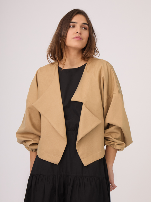 Chaqueta camel con corte asimétrico, mangas globo y fit oversized. Su material es perfecto para climas templados y cambios de estación.